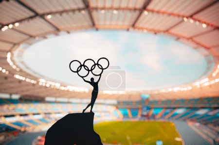 Téléchargez les photos : PARIS, FRANCE, 7 JUILLET 2023 : L'esprit olympique incarne : la statue de l'athlète tient le cercle olympique haut au stade olympique moderne. Saisir l'essence des Jeux olympiques d'été de Paris 2024. - en image libre de droit