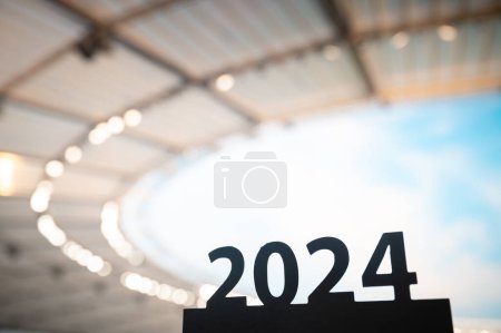 Foto de La silueta del letrero '2024' se inspira cuando comienza el año deportivo, que conduce a los juegos de verano en París. Estadio moderno en el fondo. - Imagen libre de derechos