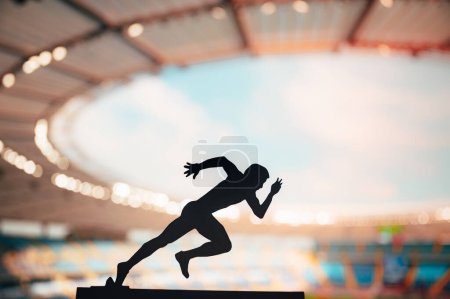 Foto de Correr a través del anochecer: silueta de un atleta masculino, un corredor de larga distancia, persiguiendo con resistencia la excelencia en un estadio deportivo moderno - Imagen libre de derechos