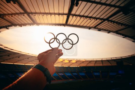 Photo for PARIS, FRANCE, JULY 7, 2023: Unveiling the Emblem: Athlete Presents Olympic Rings in Majestic Evening Glow. Photo for Summer Olympic Games in Paris 2024. - Royalty Free Image