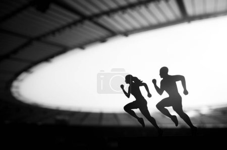 Téléchargez les photos : Silhouettes de coureurs masculins et féminins mettent en valeur la dédicace et la synergie, transcendant les limites d'un stade sportif moderne. Photo en noir et blanc - en image libre de droit