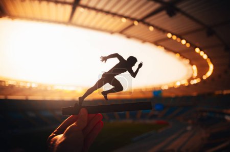 Téléchargez les photos : Chasing Glory : Silhouette d'un athlète, Primé pour la vitesse, Debout au milieu du crépuscule lumineux dans un stade de sport moderne. Lumière chaude du coucher du soleil. Modifier l'espace pour votre montage, jeux 2024 à Paris - en image libre de droit