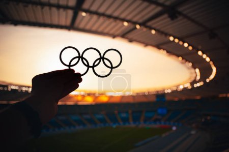 Foto de PARÍS, FRANCIA, 7 DE JULIO DE 2023: Radiating Olympic Spirit: Athlete Showcases Olympic Rings in Serene Evening Light. Foto para los Juegos Olímpicos de París 2024 - Imagen libre de derechos