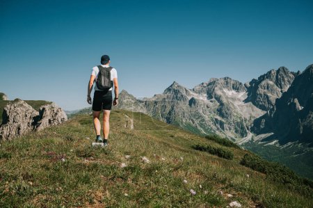 Foto de Capturado en acción, un trekker joven explora la cresta esmeralda de los Belianske Tatras, ofreciendo una vista cautivadora de los altos Tatras en la distancia - Imagen libre de derechos