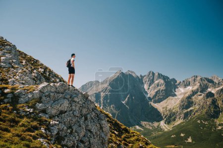 Foto de Abrazando la belleza de los Belianske Tatras, un joven viajero se deleita en la serenidad, mientras la grandeza de los High Tatras se despliega en el telón de fondo. - Imagen libre de derechos