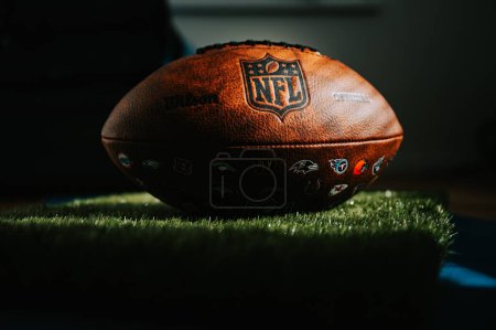 Photo for NEW YORK, USA, SEPTEMBER 11, 2023: NFL's Trademark: Leather Ball and Iconic Logo. Official National Football league ball places in shadow of athletes dressing room. Black edit space - Royalty Free Image