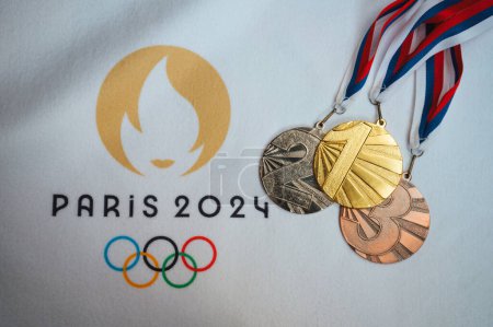 Foto de PARÍS, FRANCIA, ENERO 4. 2024: Un toque de victoria: Medallas de Oro, Plata y Bronce arregladas sobre manta blanca, París 2024 Olímpicos Logo Incluido - Imagen libre de derechos