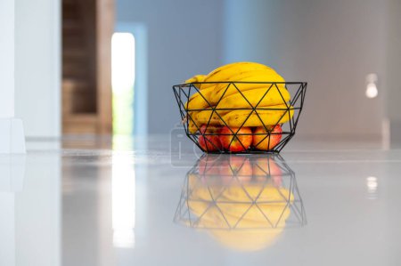 Téléchargez les photos : Une banane ensoleillée orne le comptoir de la cuisine dans un bol en verre. - en image libre de droit