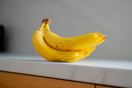 Téléchargez les photos : Banane positionnée sur la table de cuisine, éclairée par la lumière du jour - en image libre de droit