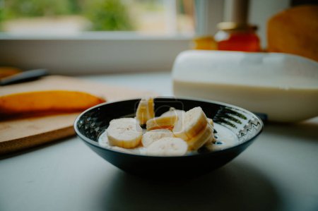 Foto de Escena del desayuno soleada: plátano emparejado con yogur y avena crujiente - Imagen libre de derechos