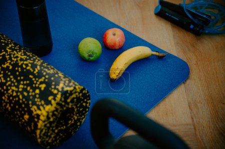 Téléchargez les photos : Une combinaison de kiwi, d'amandes et d'une serviette de gym sur le tapis. Nourrir le corps pendant une séance d'entraînement dédiée - en image libre de droit