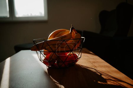 Téléchargez les photos : La lumière chaude du soleil jette une lueur sur une banane dans un bol en verre sur le comptoir de la cuisine - en image libre de droit