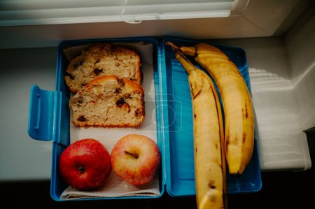 Foto de Paquete de desayuno para la escuela o el trabajo. Plátano, manzanas y pan de plátano envuelto para una merienda - Imagen libre de derechos