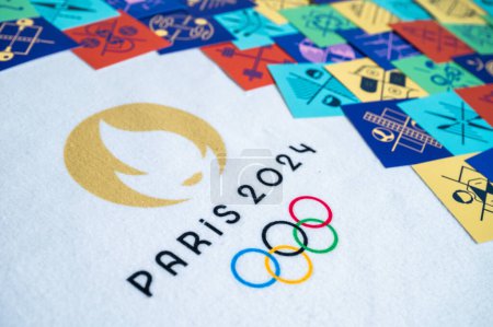 Foto de PARÍS, FRANCIA, 26 DE MARZO DE 2024: El logotipo oficial de los Juegos Olímpicos de París 2024 contra un tapiz de tarjetas de pictograma que ilustran cada deporte olímpico con iconos oficiales - Imagen libre de derechos