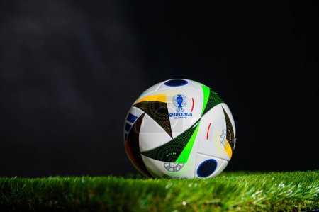Téléchargez les photos : HAMBURG, ALLEMAGNE, 17 AVRIL 2024 : Ballon officiel de football Adidas Fussballliebe pour le tournoi de football Euro 2024, placé sur l'herbe verte. Fond noir, éditer l'espace Tournoi européen en Allemagne - en image libre de droit