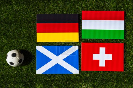Foto de Alemania lidera el Grupo A: Banderas de Alemania, Escocia, Hungría, Suiza y pelota de fútbol sobre hierba verde en el torneo de fútbol de Europa en Alemania en 2024 - Imagen libre de derechos