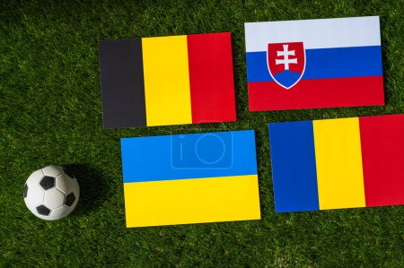 Bélgica lidera el Grupo E: Banderas de Bélgica, Eslovaquia, Rumania, Ucrania y pelota de fútbol sobre hierba verde en el torneo de fútbol de Europa en Alemania en 2024