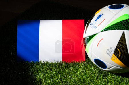 Téléchargez les photos : BERLIN, GERMANY, APRIL 17, 2024: France national flag and official soccer ball of Euro 2024 football tournament in Germany placed on green grass. Black background, edit space - en image libre de droit