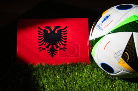 Foto de LEIPZIG, ALEMANIA, 17 DE ABRIL DE 2024: Bandera nacional de Albania y balón de fútbol oficial del torneo de fútbol Euro 2024 en Alemania colocado sobre hierba verde. Fondo negro, editar espacio - Imagen libre de derechos
