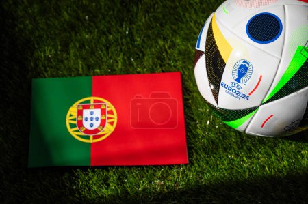 Téléchargez les photos : MUNICH, ALLEMAGNE, 17 AVRIL 2024 : Drapeau national du Portugal et ballon de football officiel du tournoi de football Euro 2024 en Allemagne placé sur l'herbe verte. Arrière-plan noir, modifier l'espace - en image libre de droit