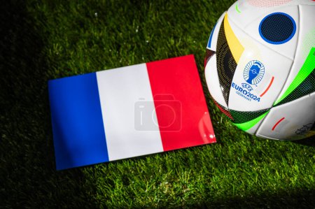 Téléchargez les photos : MUNICH, GERMANY, APRIL 17, 2024: France national flag and official soccer ball of Euro 2024 football tournament in Germany placed on green grass. Black background, edit space - en image libre de droit