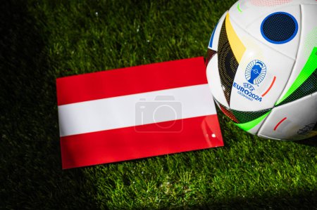 Téléchargez les photos : LEIPZIG, ALLEMAGNE, 17 AVRIL 2024 : drapeau national autrichien et ballon de football officiel du tournoi de football Euro 2024 en Allemagne placé sur l'herbe verte. Arrière-plan noir, modifier l'espace - en image libre de droit