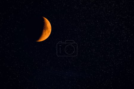 La luna naranja es creciente por la noche, un satélite natural contra el cielo estrellado.