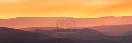 Ostsudeten, farbenfroher Sonnenuntergang über den Bergen, Blick vom Wanderweg auf die Bergkette und das Tal.