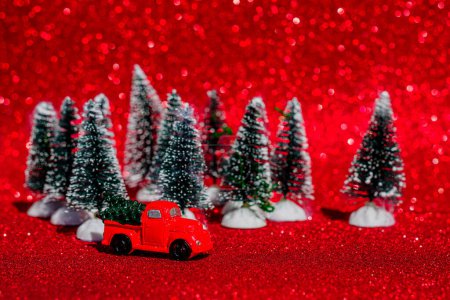 Téléchargez les photos : Voiture jouet rétro rouge, camion portant un petit sapin de Noël sur le fond d'un bokeh de Noël. Des cartes de Noël. Truck.Delivery service - en image libre de droit