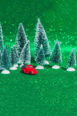 Photo for Red retro toy car, truck carrying a small Christmas tree on the background of a Christmas bokeh. Christmas cards. Truck.Delivery service - Royalty Free Image