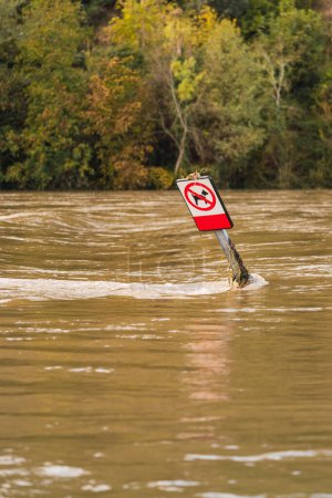 Téléchargez les photos : Panneau routier et trottoir inondés en raison du débordement de la rivière dû à la pluie constante. - en image libre de droit