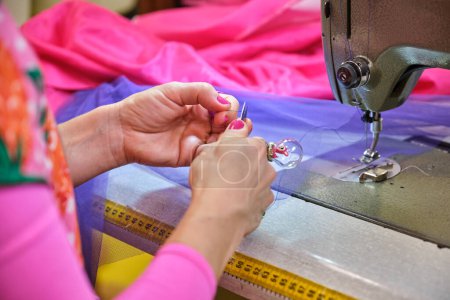 Photo for Unrecognizable dressmaker cutting the thread to threading sewing machine in a sewing workshop. - Royalty Free Image