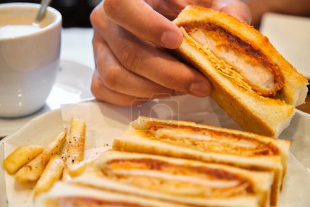 Foto de Sándwich japonés katsu sando de mano con chuleta de cerdo empanada, col y salsa tonkatsu en una cafetería. - Imagen libre de derechos