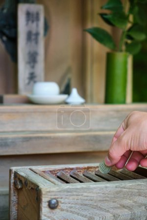 Photo for Hand making a offering in wooden offering box or Saisen Box, in Japanese Temple, Kyoto, Japan. - Royalty Free Image