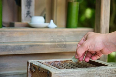 Photo for Hand making a offering in wooden offering box or Saisen Box, in Japanese Temple, Kyoto, Japan. - Royalty Free Image