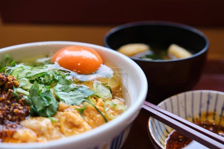Photo for Oyakodon set, bowl of rice topped with chicken and eggs, and miso soup with kitsune tofu and wakame seaweed at a restaurant. - Royalty Free Image