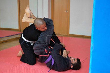 Foto de Dos hombres practicando Jiu-Jitsu brasileño luchando en la escuela. Formación BJJ. - Imagen libre de derechos