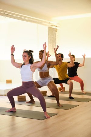 Eine Gruppe von Menschen praktiziert in einem Raum Yoga, Utkata Konasana oder Göttin. Die Szene ist ruhig und friedlich, da die Frauen sich auf ihre Posen und Atmung konzentrieren.