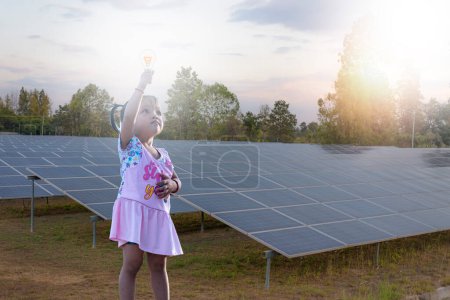 Téléchargez les photos : Girl hand holding bright light bulb at solar farm showing creative business strategy with light bulb as concept. - en image libre de droit