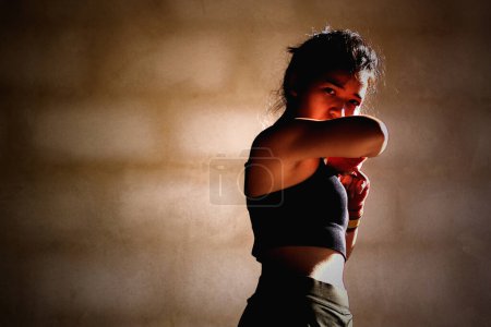 Photo for Young woman practicing boxing at the gym, she wears boxing gloves. - Royalty Free Image