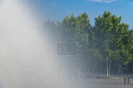 Téléchargez les photos : Movement transparent splash. Sparkling gush water of liquid drops detail. Fountain flows like of stream in the city in sunny weather. Refreshing cool water on hot day. Sprays in summertime close up. - en image libre de droit