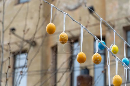 Photo for Colorful handmade egges for easter in branches outdoor. Decorating trees with hanging eastereggs in city street. Tradition holiday on christianity religion. Symbol of resurrection to new life. - Royalty Free Image