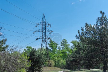 Electricity transmission towers and power lines in forest. High voltage pole on road. Energy concept of industry in countryside. Crisis and problems in energy sector. Communications and power supply.