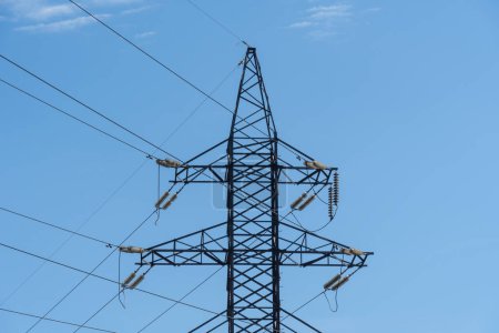 Strommasten und Stromleitungen in blauem Himmel. Detail Hochspannungsmast. Energiekonzept der Industrie. Kommunikation und Stromversorgung. Krise und Probleme im Energiesektor. Infrastruktur