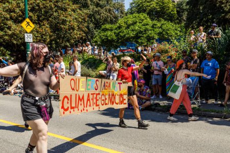 Foto de Vancouver, Canadá - 31 de julio de 2022: La gente camina por la calle Pacific Street con un enorme cartel de Queers Against Climate Genocide durante el Desfile del Orgullo - Imagen libre de derechos