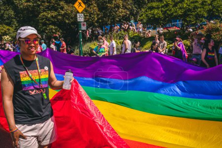 Foto de Vancouver, Canadá - 31 de julio de 2022: La gente camina por Pacific Street con una enorme bandera arcoíris durante el Desfile del Orgullo - Imagen libre de derechos