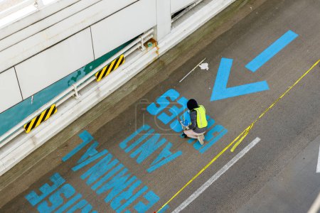 Téléchargez les photos : Vancouver, Canada - 18 mars 2023 : Un travailleur peint des panneaux sur la route avec le message "Terminal de croisière et autobus seulement" - en image libre de droit