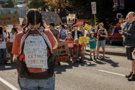 Foto de Vancouver, Canadá - 15 de septiembre de 2023: Una niña con una mochila llevando muchos eslóganes como parte de la Huelga Climática Global - Imagen libre de derechos