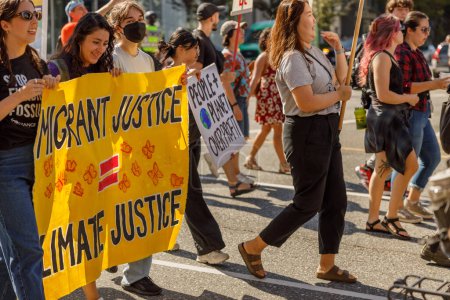 Foto de Vancouver, Canadá - 15 de septiembre de 2023: Jóvenes activistas con un cartel: Justicia Migrante Justicia Climática caminando por Cambie Street como parte de la Huelga Climática Global en Vancouver - Imagen libre de derechos
