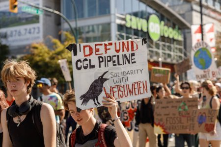 Foto de Vancouver, Canadá - 15 de septiembre de 2023: Jóvenes activistas con un cartel: Defund GGL pipeline (Solidaridad con Wetsuweten) caminando por Cambie Street como parte de la Huelga Climática Global en Vancouver - Imagen libre de derechos